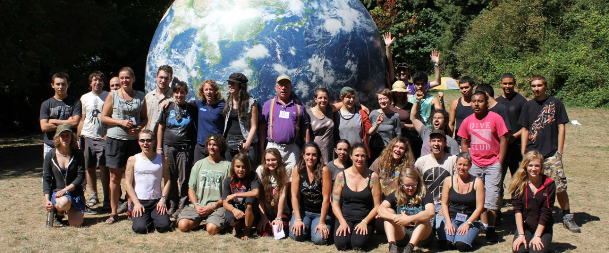 Youth posing outside for a picture in front of a giant globe