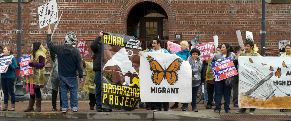 Adults holding large signs and yelling while protesting on the side of a street
